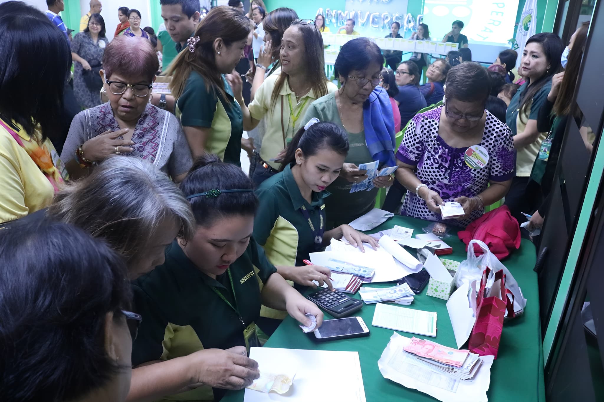 NOVADECI staff assisting members at a service counter during an anniversary event