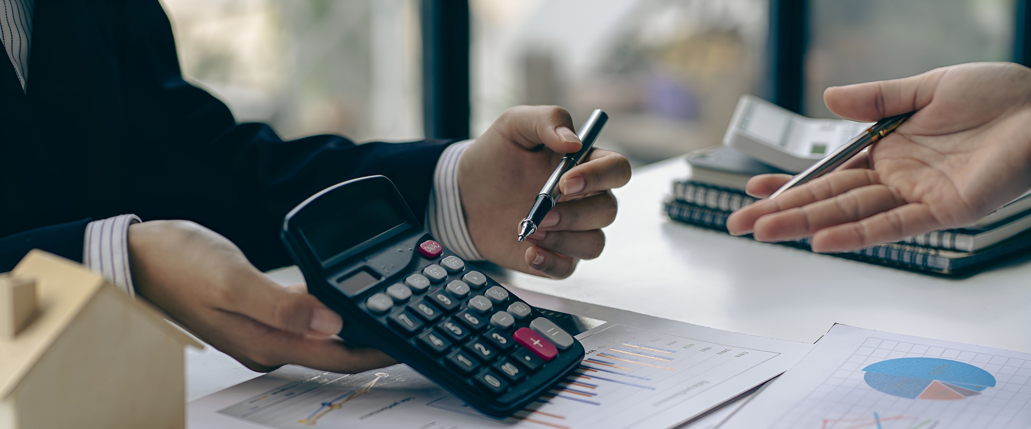 Hands reviewing financial documents with a calculator and pen, representing NOVADECI back to back loans