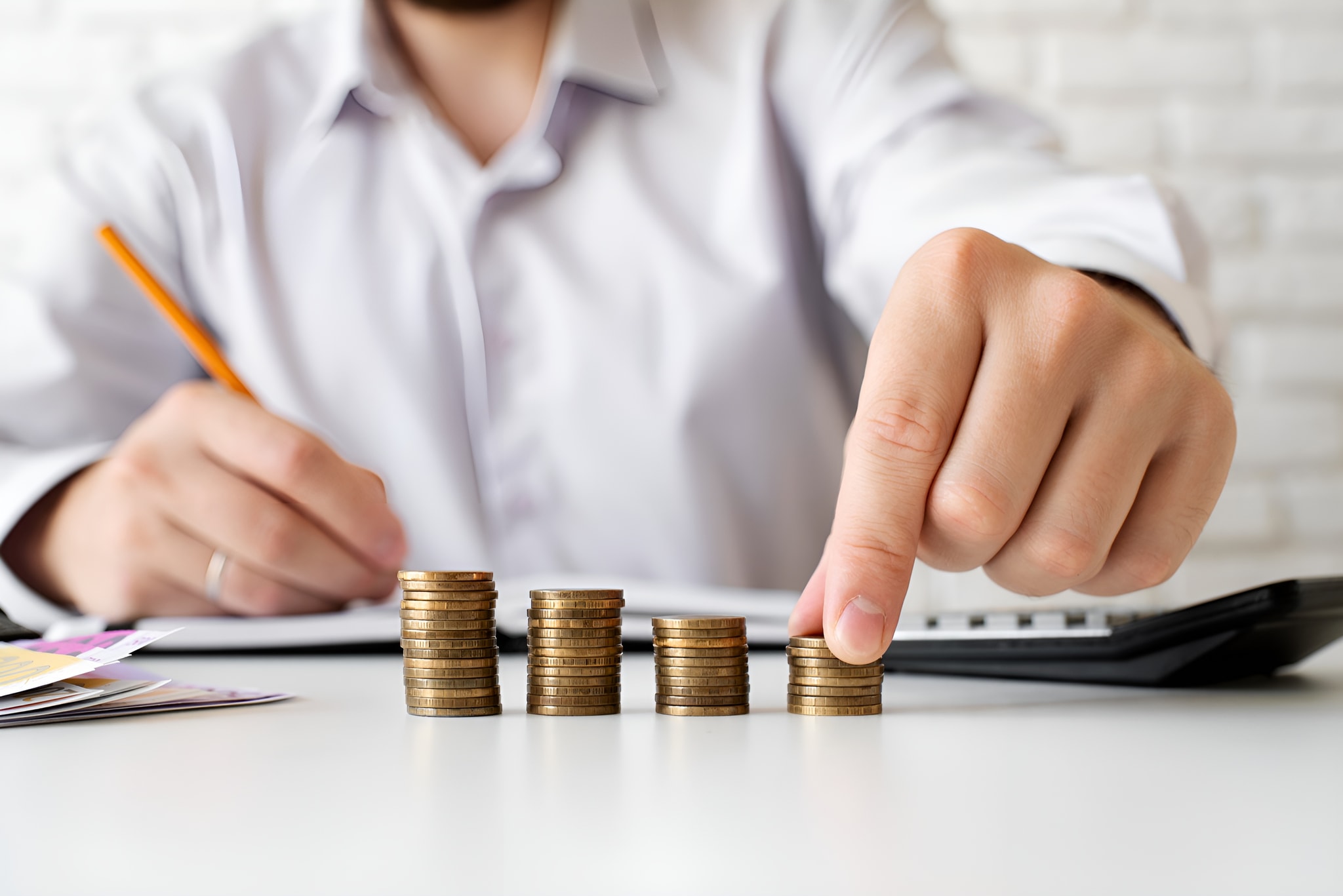 Hand stacking coins beside a calculator, representing NOVADECI business loan financing