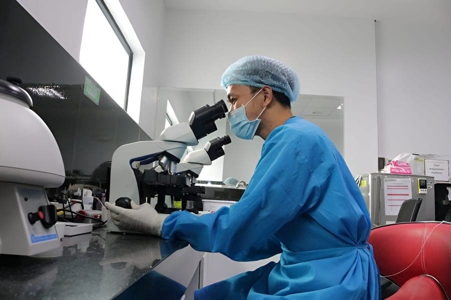 Laboratory technician examining a specimen under a microscope